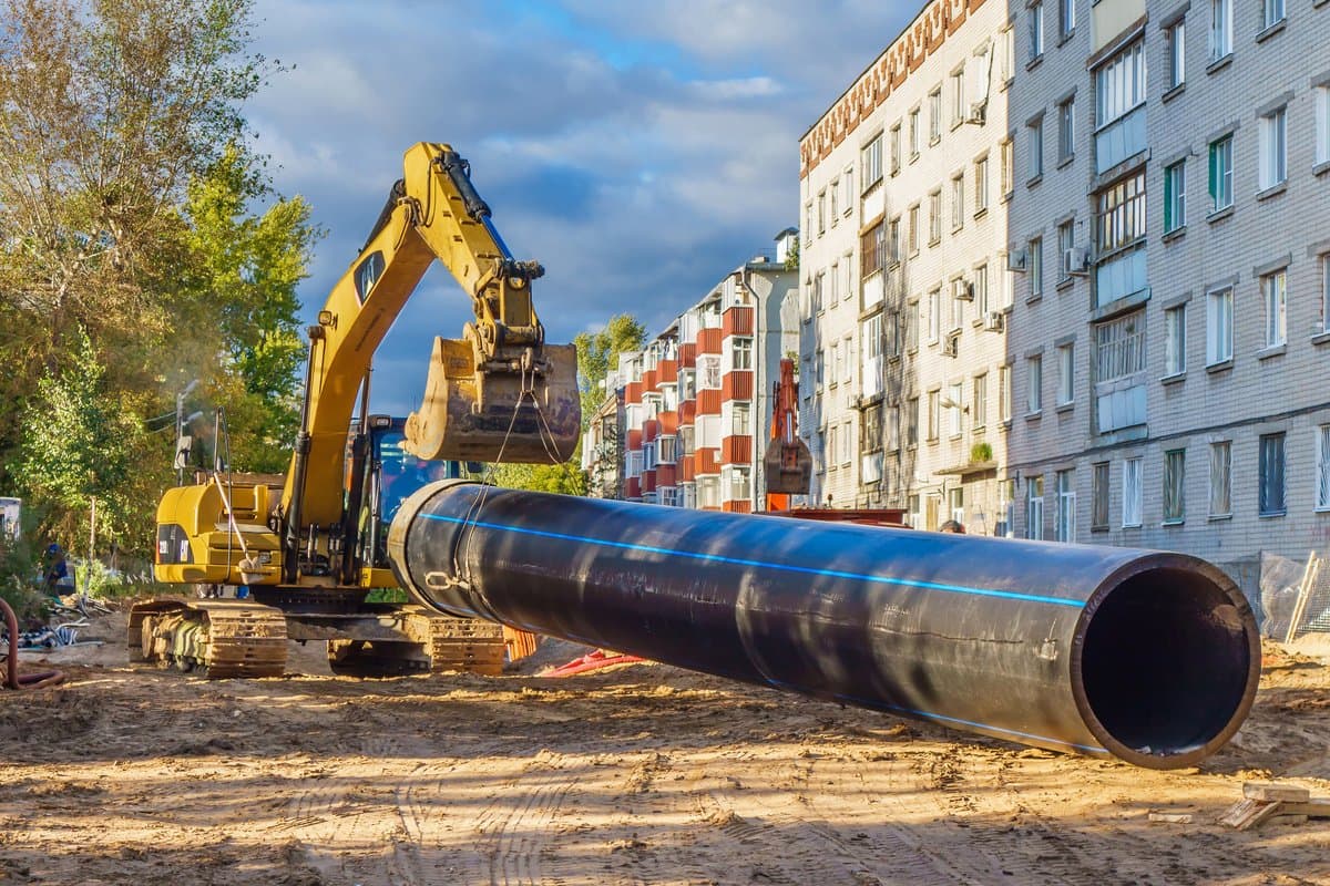 Plumbing crew installing a PVC spot repair with shear-banded couplings inside a clean trench